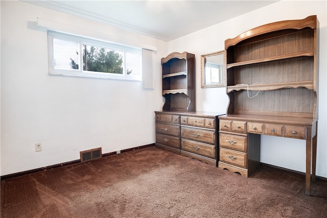 unfurnished office featuring built in desk and dark carpet