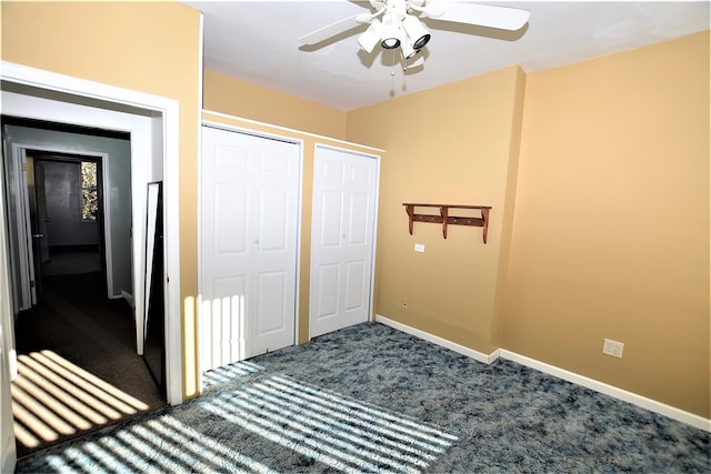 unfurnished bedroom with carpet flooring, ceiling fan, and two closets