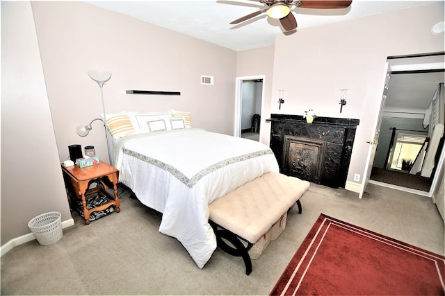 carpeted bedroom with ceiling fan and a fireplace