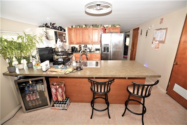 kitchen featuring a breakfast bar, stainless steel appliances, beverage cooler, sink, and lofted ceiling