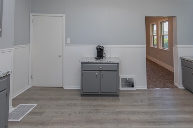 kitchen featuring light hardwood / wood-style floors, light stone countertops, and gray cabinets