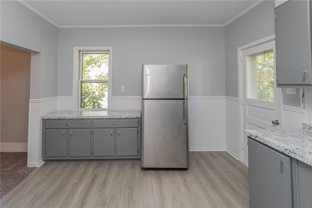 kitchen featuring crown molding, stainless steel refrigerator, light hardwood / wood-style flooring, and gray cabinets