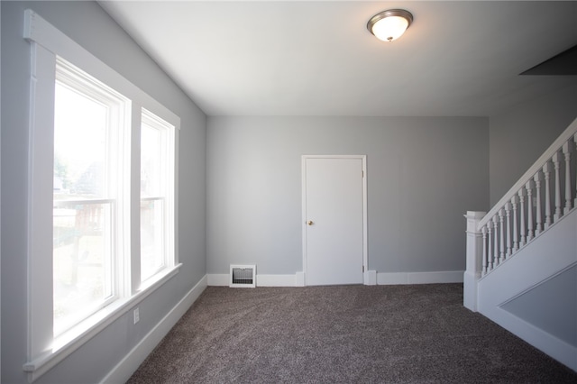 empty room featuring a healthy amount of sunlight and dark carpet