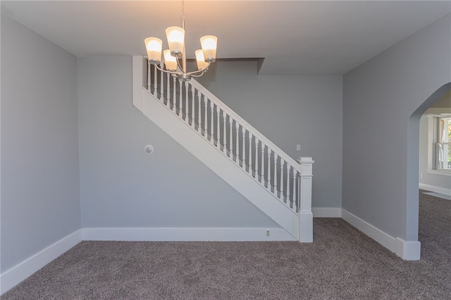 stairway with carpet floors and an inviting chandelier