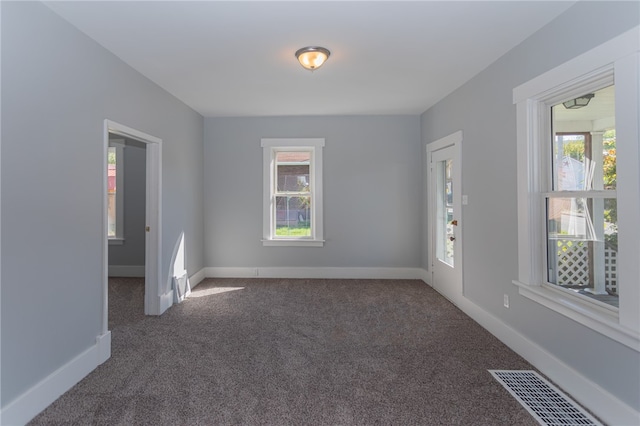 empty room with a healthy amount of sunlight and dark colored carpet