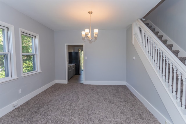 unfurnished room with carpet and an inviting chandelier