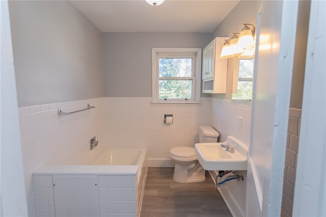 bathroom with hardwood / wood-style flooring, tile walls, toilet, a washtub, and sink