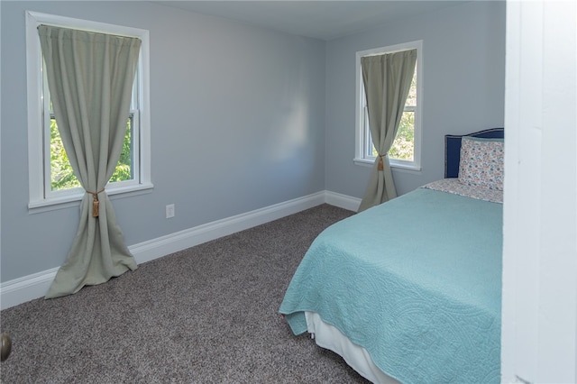 bedroom with multiple windows and dark carpet