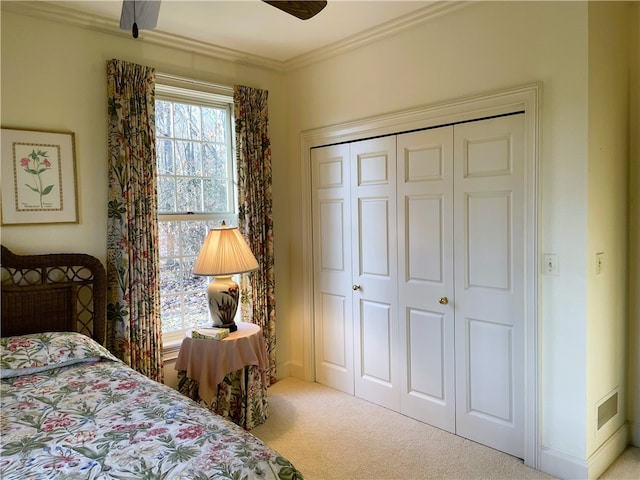 carpeted bedroom featuring crown molding, a closet, and ceiling fan