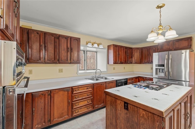 kitchen featuring appliances with stainless steel finishes, sink, decorative light fixtures, a chandelier, and a kitchen island