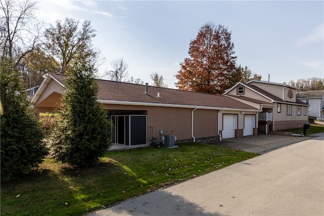 view of home's exterior with a garage, central air condition unit, and a lawn