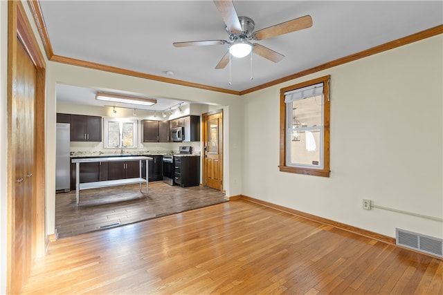 kitchen featuring crown molding, stainless steel appliances, dark brown cabinets, and light hardwood / wood-style flooring