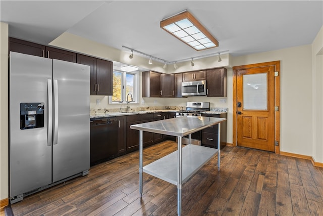 kitchen featuring light stone counters, appliances with stainless steel finishes, dark hardwood / wood-style floors, dark brown cabinetry, and sink