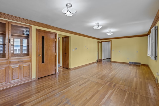 spare room with ornamental molding and light wood-type flooring