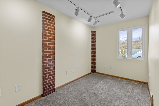 empty room featuring carpet flooring and track lighting