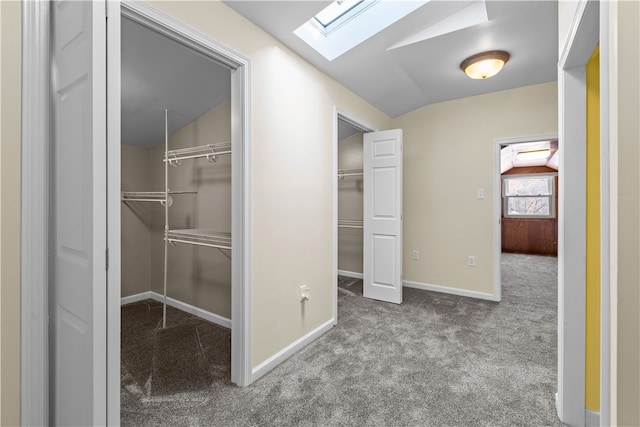 hall featuring vaulted ceiling with skylight and light colored carpet