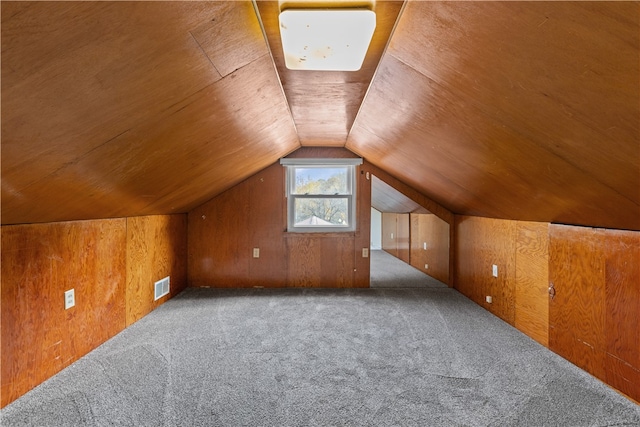 additional living space with wooden walls, carpet flooring, and vaulted ceiling