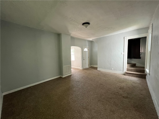 unfurnished room with dark colored carpet and a textured ceiling