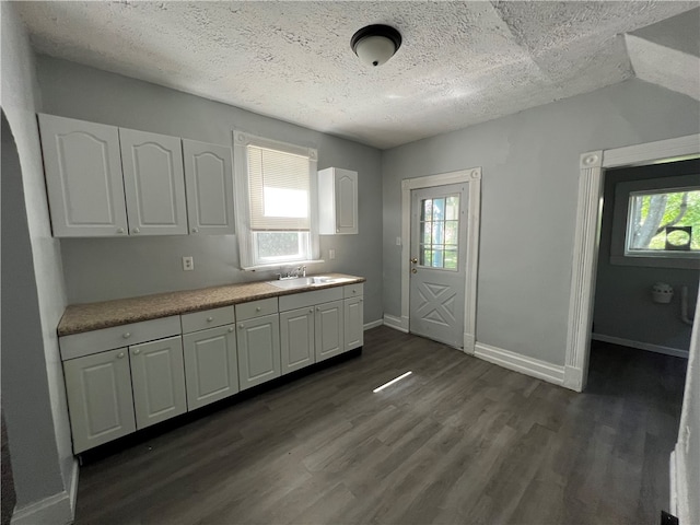 kitchen with white cabinets, a textured ceiling, sink, and dark hardwood / wood-style flooring