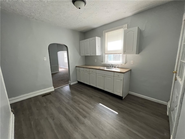 kitchen featuring white cabinets, sink, dark wood-type flooring, and a textured ceiling