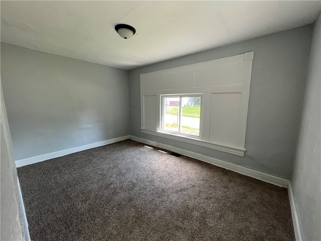 spare room featuring dark carpet