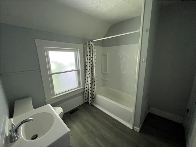 full bathroom featuring hardwood / wood-style floors, vaulted ceiling, toilet, shower / bath combo, and sink