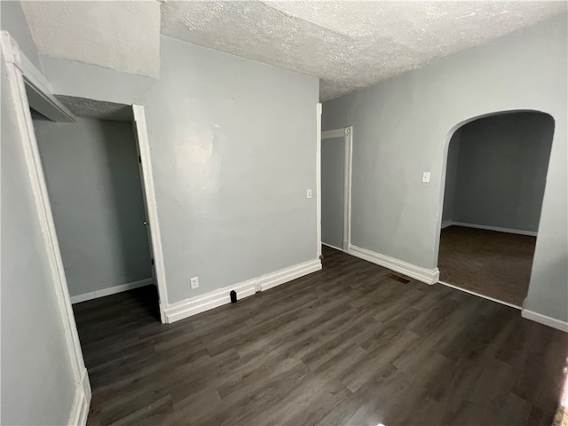 unfurnished bedroom with a closet, a textured ceiling, and dark hardwood / wood-style flooring