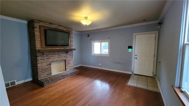 unfurnished living room with crown molding, a brick fireplace, and dark hardwood / wood-style floors