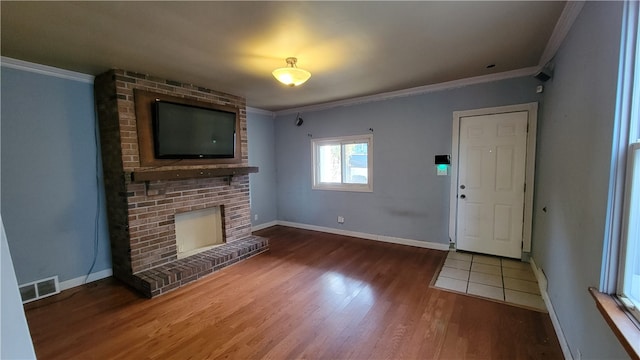 unfurnished living room with ornamental molding, a brick fireplace, and wood-type flooring