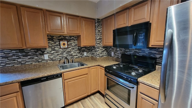 kitchen with sink, appliances with stainless steel finishes, light hardwood / wood-style flooring, and backsplash