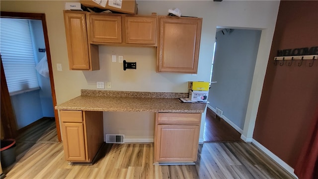 kitchen with built in desk and light wood-type flooring