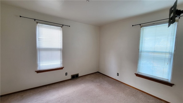 unfurnished room with a wealth of natural light and light carpet