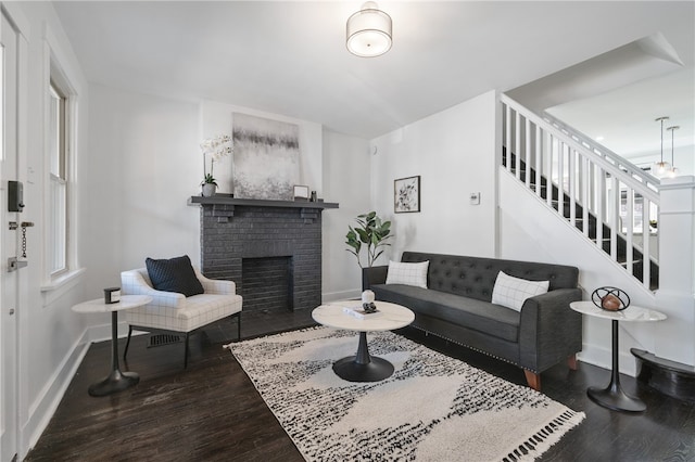 living room featuring dark hardwood / wood-style flooring and a brick fireplace