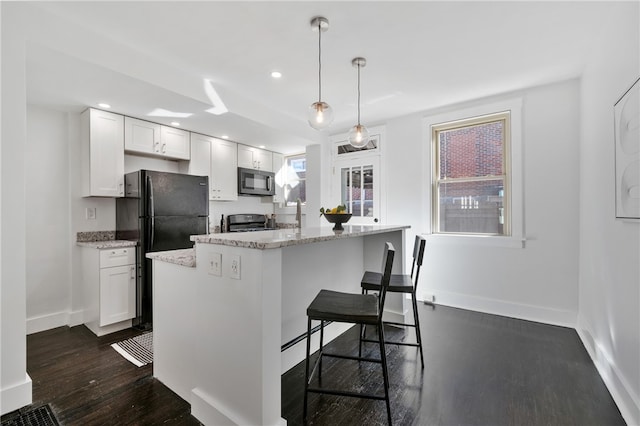 kitchen featuring black appliances, decorative light fixtures, a kitchen island, and white cabinets