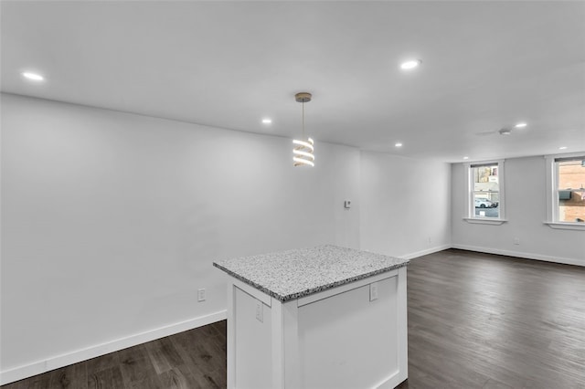 kitchen with a center island, dark hardwood / wood-style floors, decorative light fixtures, and light stone counters