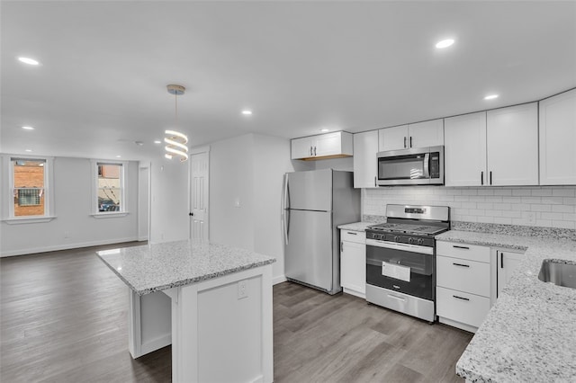 kitchen featuring dark hardwood / wood-style flooring, white cabinetry, stainless steel appliances, pendant lighting, and a center island