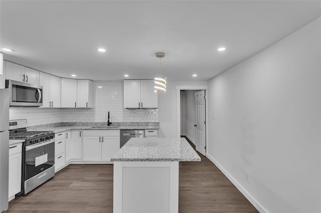 kitchen featuring appliances with stainless steel finishes, white cabinetry, sink, and pendant lighting