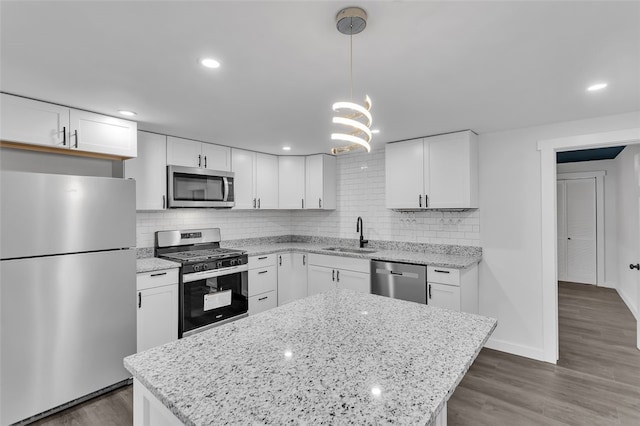 kitchen featuring hanging light fixtures, appliances with stainless steel finishes, dark hardwood / wood-style floors, and white cabinets