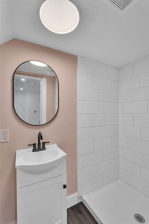 bathroom featuring vanity, hardwood / wood-style floors, vaulted ceiling, and tiled shower