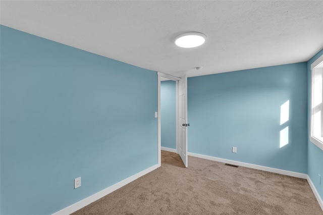 carpeted empty room featuring a textured ceiling