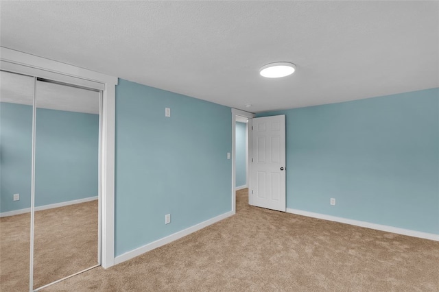 unfurnished bedroom with a closet, light carpet, and a textured ceiling