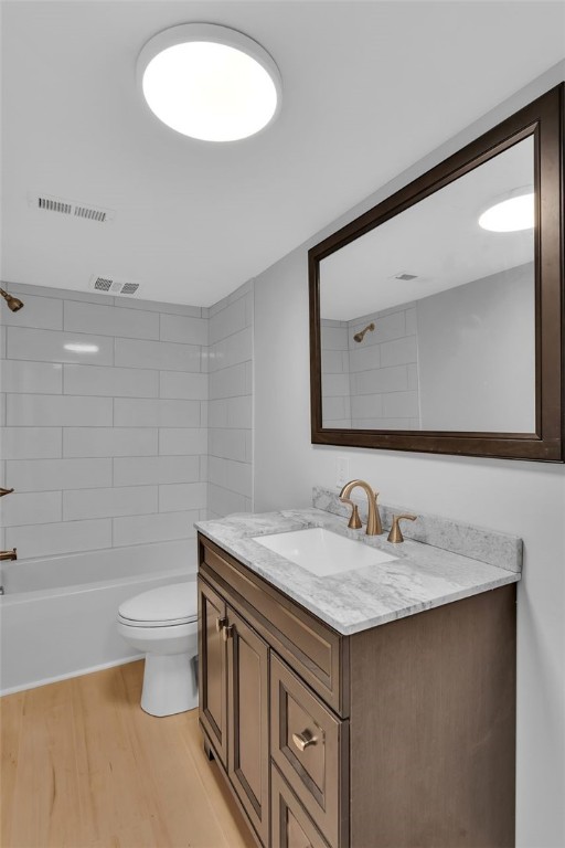 full bathroom with vanity, toilet, tiled shower / bath combo, and wood-type flooring