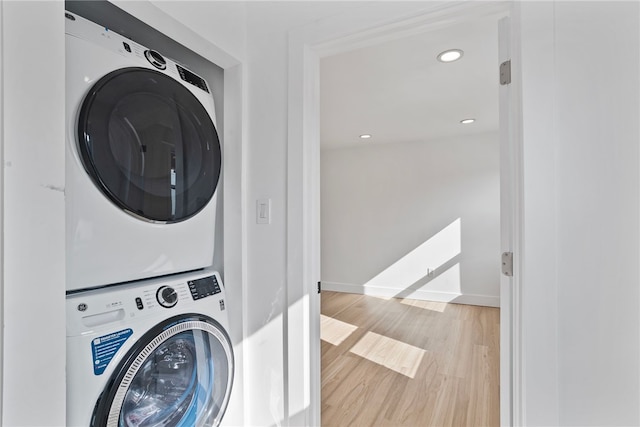 laundry room with stacked washer / drying machine and light wood-type flooring