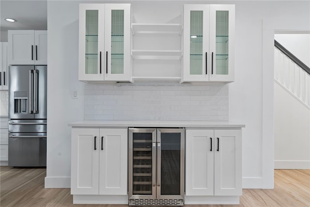 bar featuring white cabinetry, light wood-type flooring, high end fridge, and beverage cooler