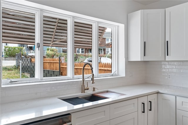 kitchen featuring a healthy amount of sunlight, decorative backsplash, sink, and white cabinets