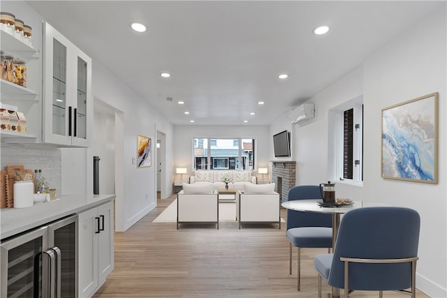 living room with a fireplace, light hardwood / wood-style flooring, a wall unit AC, and beverage cooler