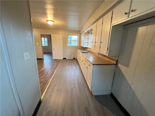 kitchen with wood-type flooring, sink, and white cabinets