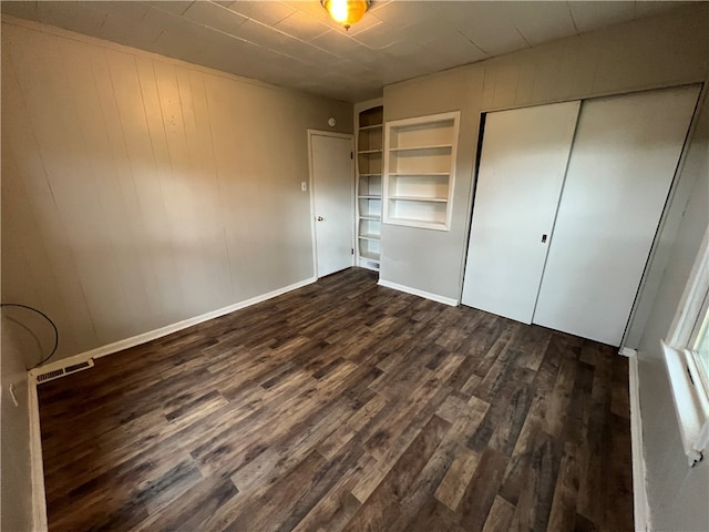 unfurnished bedroom with a closet and dark hardwood / wood-style flooring