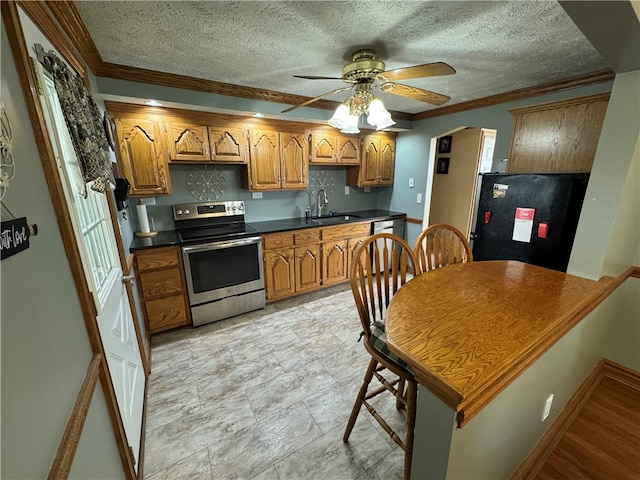 kitchen with sink, stainless steel range with electric stovetop, a textured ceiling, black fridge, and ornamental molding