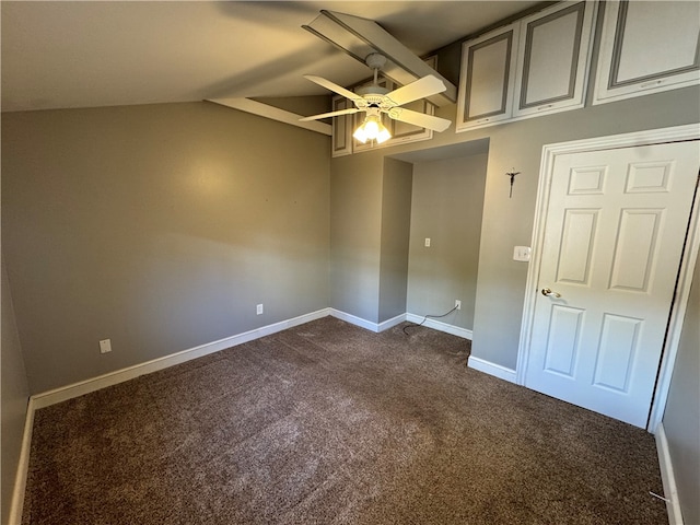 unfurnished room featuring dark carpet, vaulted ceiling, and ceiling fan